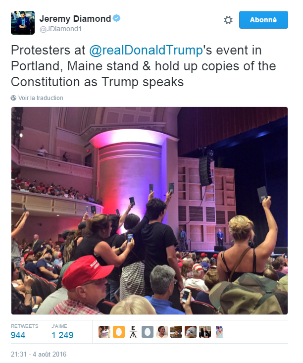 Traduction: Des protestataires au meeting de Donald Trump à Portland, Maine se lèvent et brandissent des copies de la Constitution pendant que Trump parle.